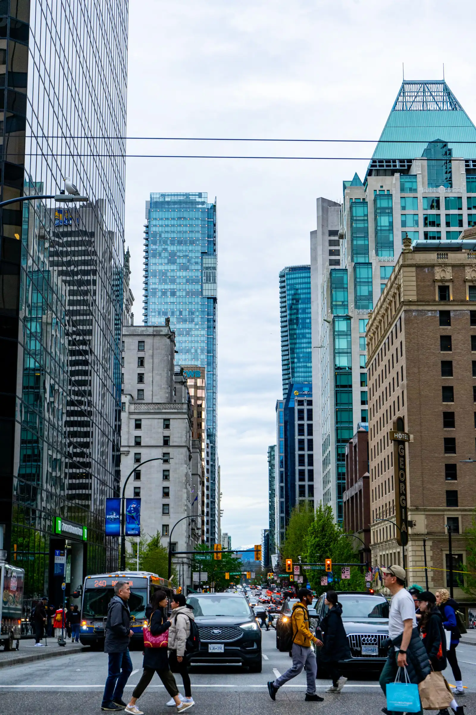 People and traffic on a downtown Vancouver street lined with towers in spring